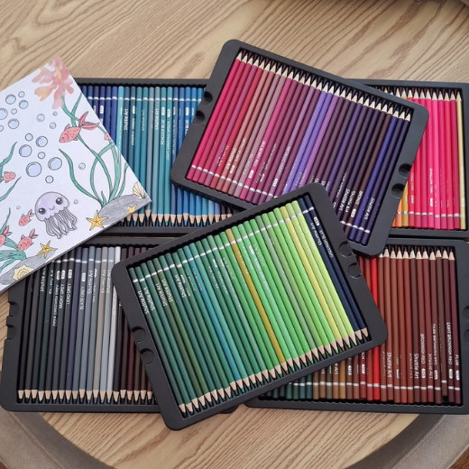 Pencils de couleur disposés sur une table, accompagnés d'un livre à colorier.