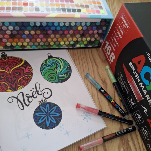 Dessin de boules de Noël colorées avec des marqueurs et une boîte de feutres.